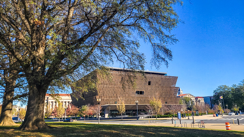 brown building of the national museum of african american history framed by tree