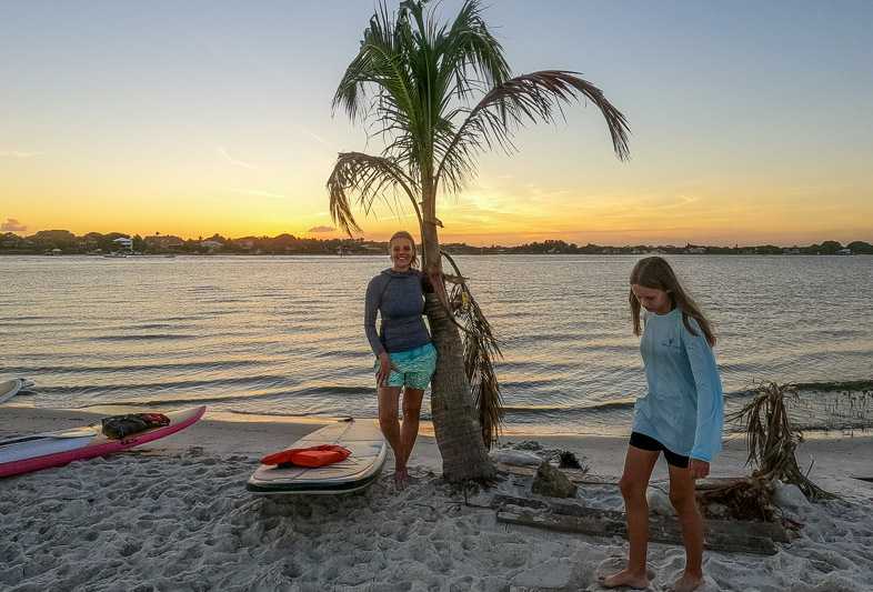 people standing next to a palm tree on the beach
