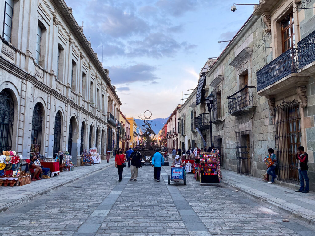 People walking down a street in Oaxaca, Mexico surrounded by buildings